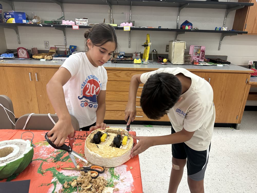 Two students wiring motors into a mycelium rover body