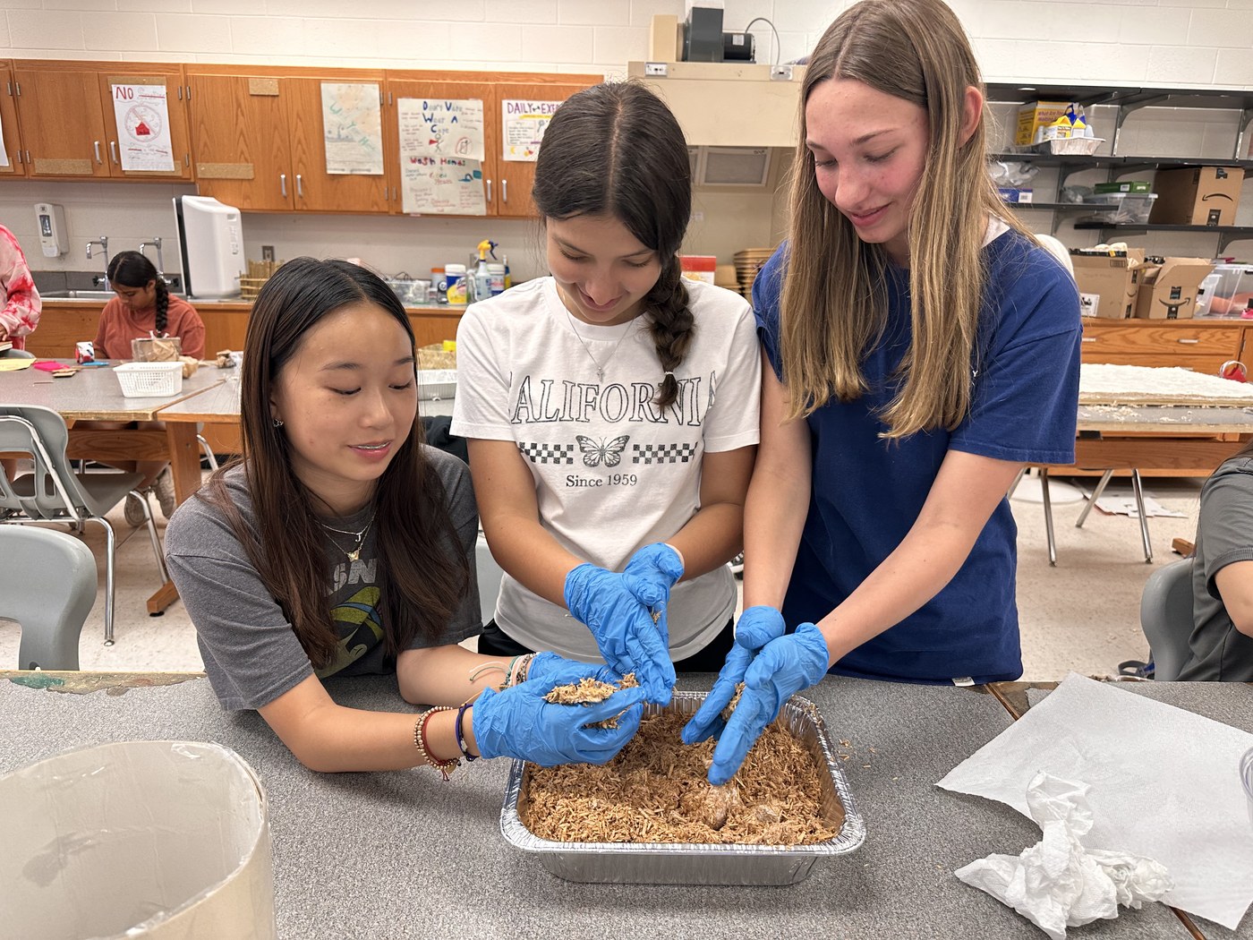 Summer Innovation Academy students packing a mycelium and biomaterials mould in the lab