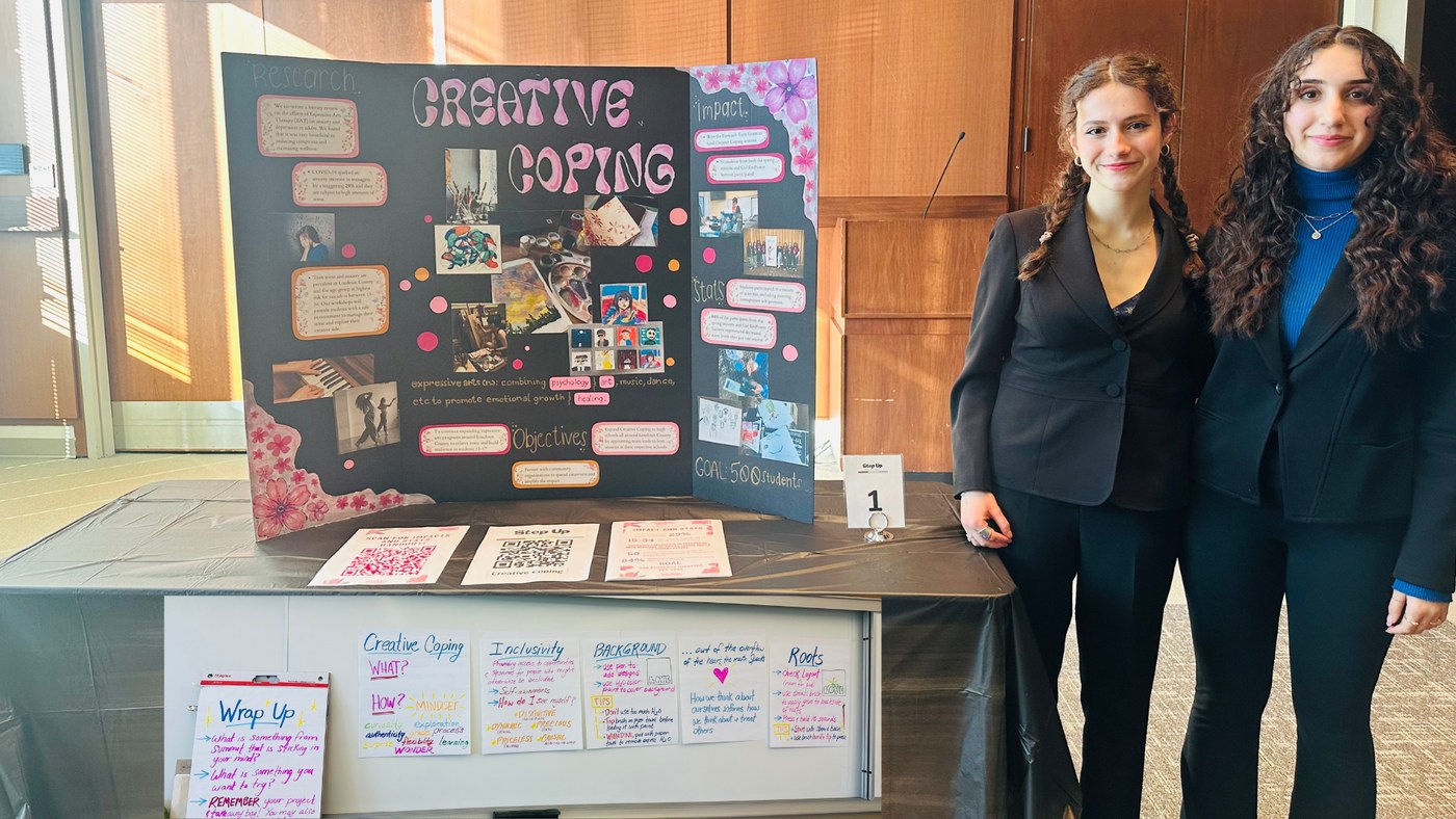 Mahsa and Katarina presenting their Creative Coping project board at a community showcase